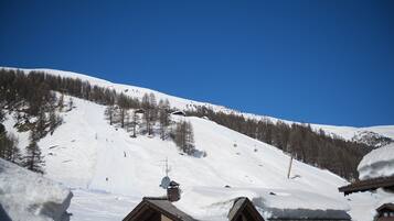 A snow-covered mountain with ski lifts and a few buildings at the base.
