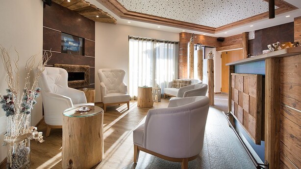 A modern living room with white leather sofas, a wooden coffee table, and a fireplace. - Garnì Oasi (Livigno)