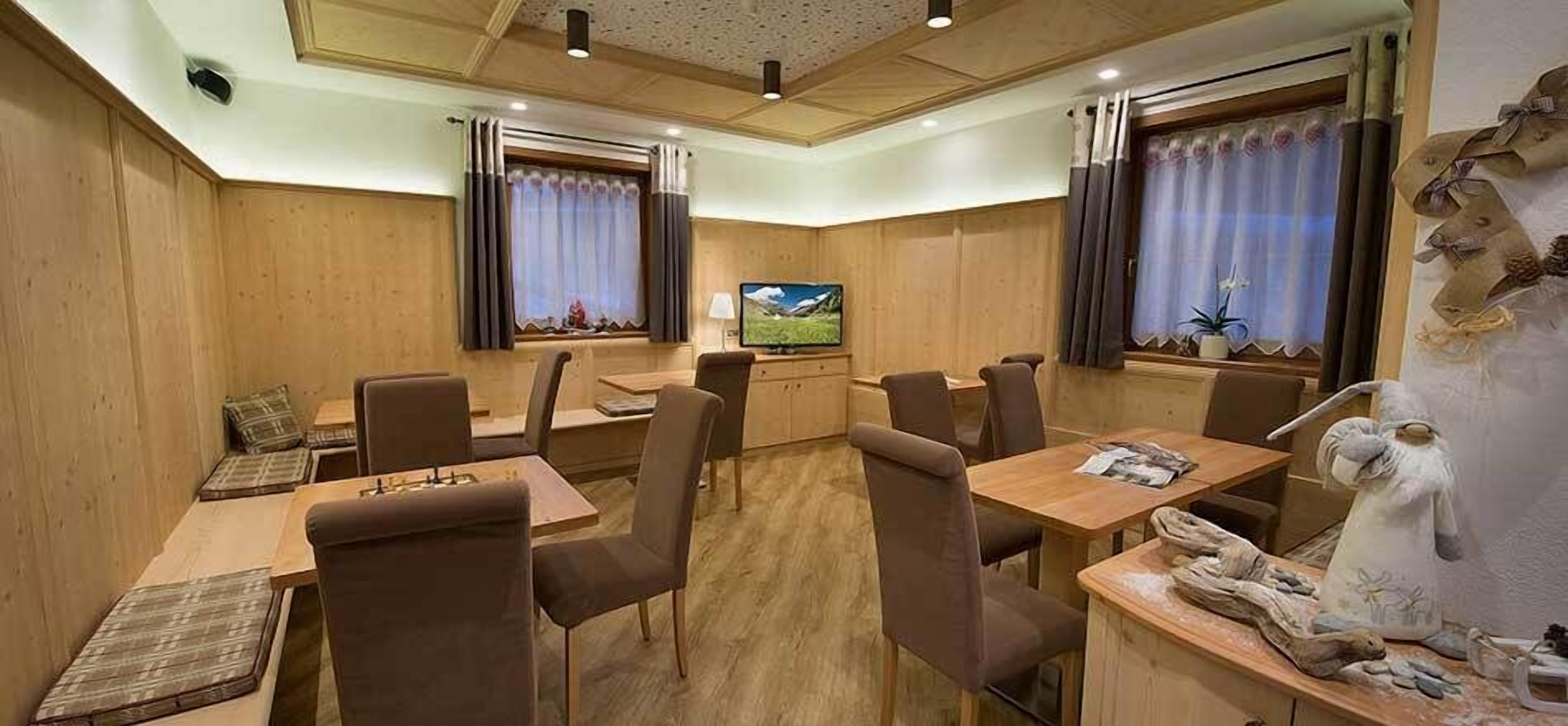 Un espace repas avec des murs en bois, plusieurs tables et chaises, un téléviseur et des objets décoratifs.