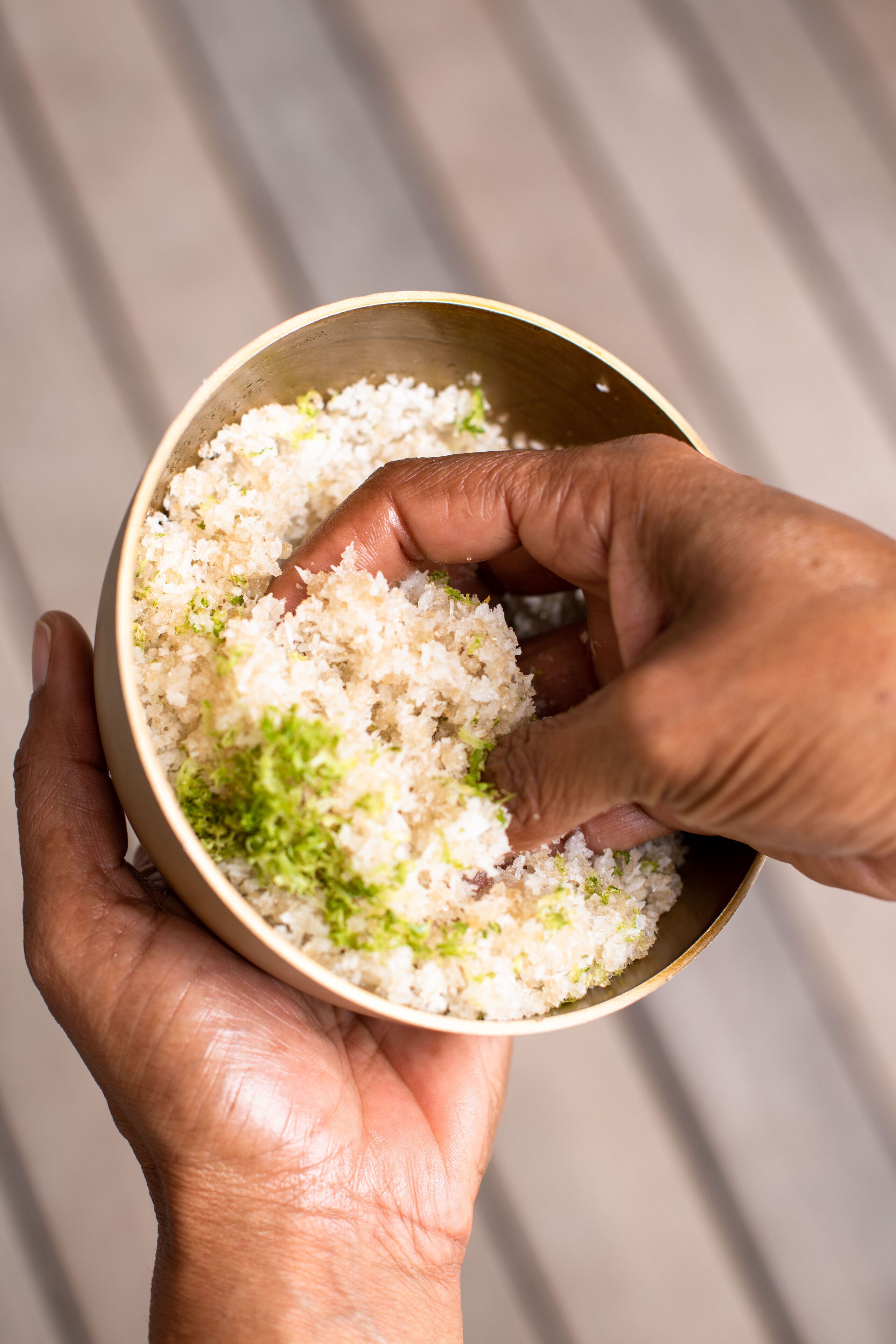 Una mano sosteniendo un tazón de arroz con guarnición verde.