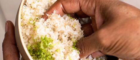 Una mano sosteniendo un tazón de arroz con guarnición verde.