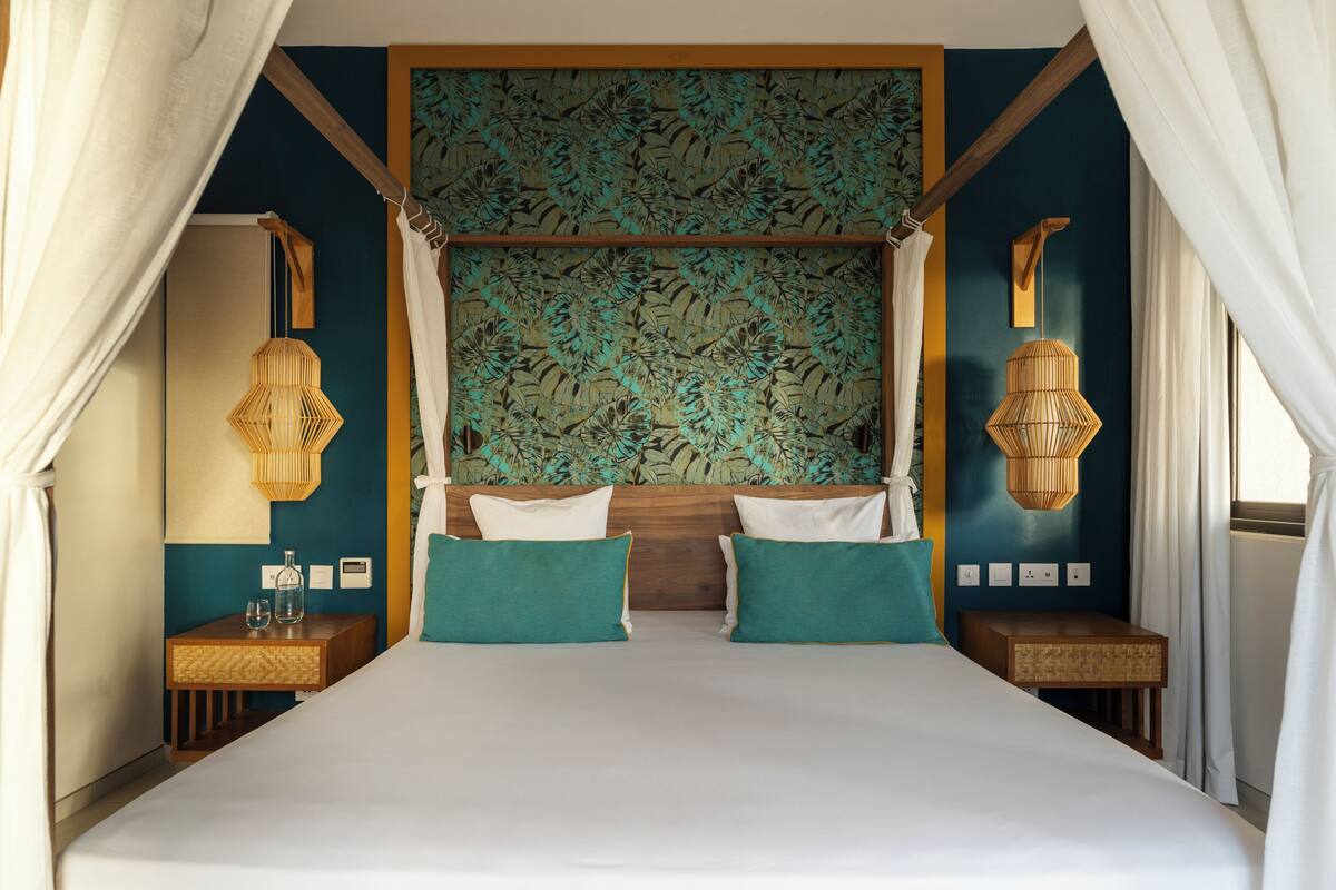 Une chambre à coucher avec un lit à baldaquin, deux tables de chevet et une lampe fixée au mur.