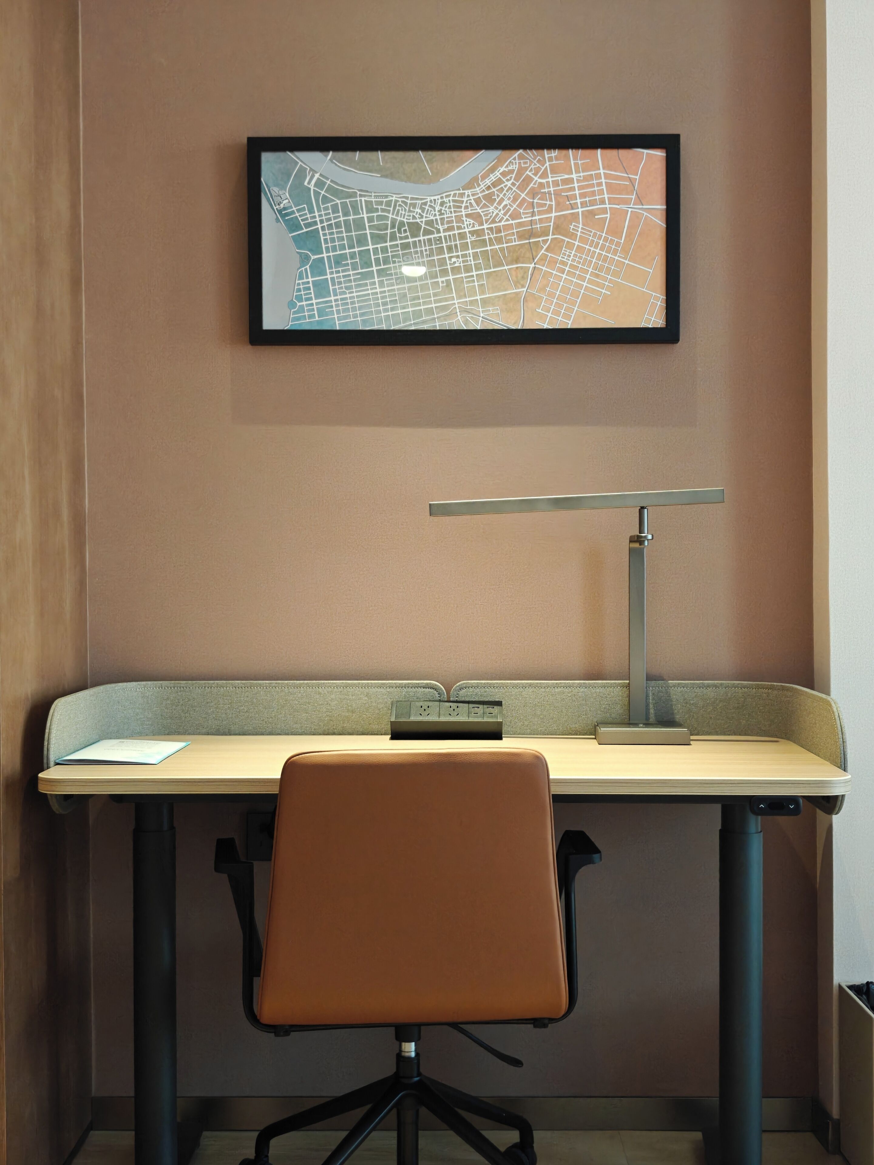 A workspace with a desk, chair, and a wall-mounted map.