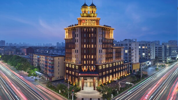 Un Hilton Garden Inn de varios pisos con una torre distintiva y señalización iluminada.