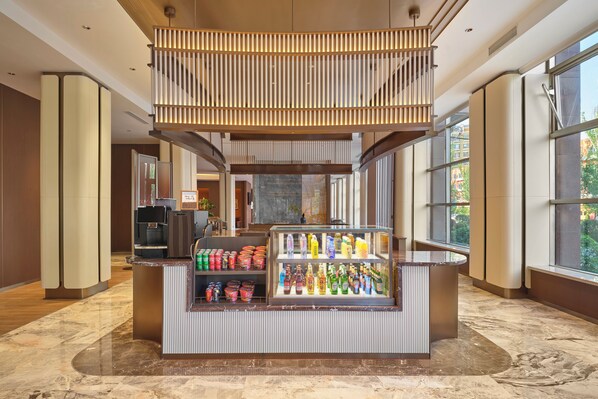A hotel lobby with a reception desk, a beverage display, and large windows offering a view of the outside. - Hilton Garden Inn Yingkou Zhanqian (Yingkou)