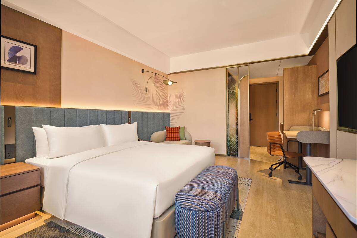 Una habitación de hotel moderna con una cama grande, un escritorio y una silla.