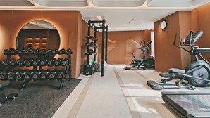 Un gimnasio con equipo de levantamiento de pesas, cintas de correr y un espejo grande.