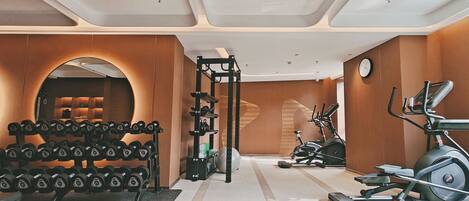 A gym with weightlifting equipment, treadmills, and a mirrored wall.