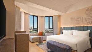Una habitación de hotel moderna con una cama grande, un sofá, una mesita y un televisor.