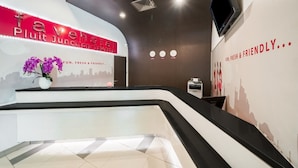 A reception area with a modern design, featuring a reception desk, a wall-mounted TV, and a cityscape mural.