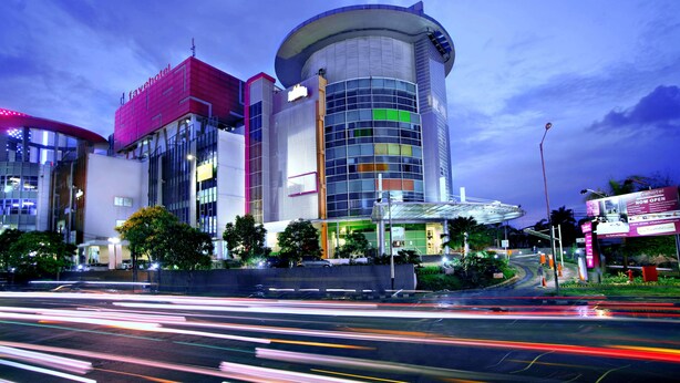 A modern hotel with a curved facade, multiple floors, and a prominent glass entrance.