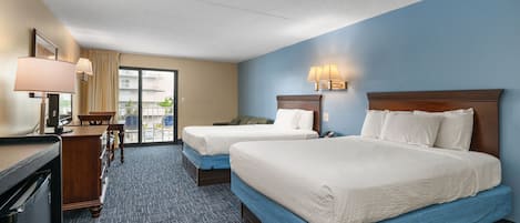 Quarto de hotel com duas camas, uma escrivaninha, uma cadeira, um abajur e vista para o exterior.
