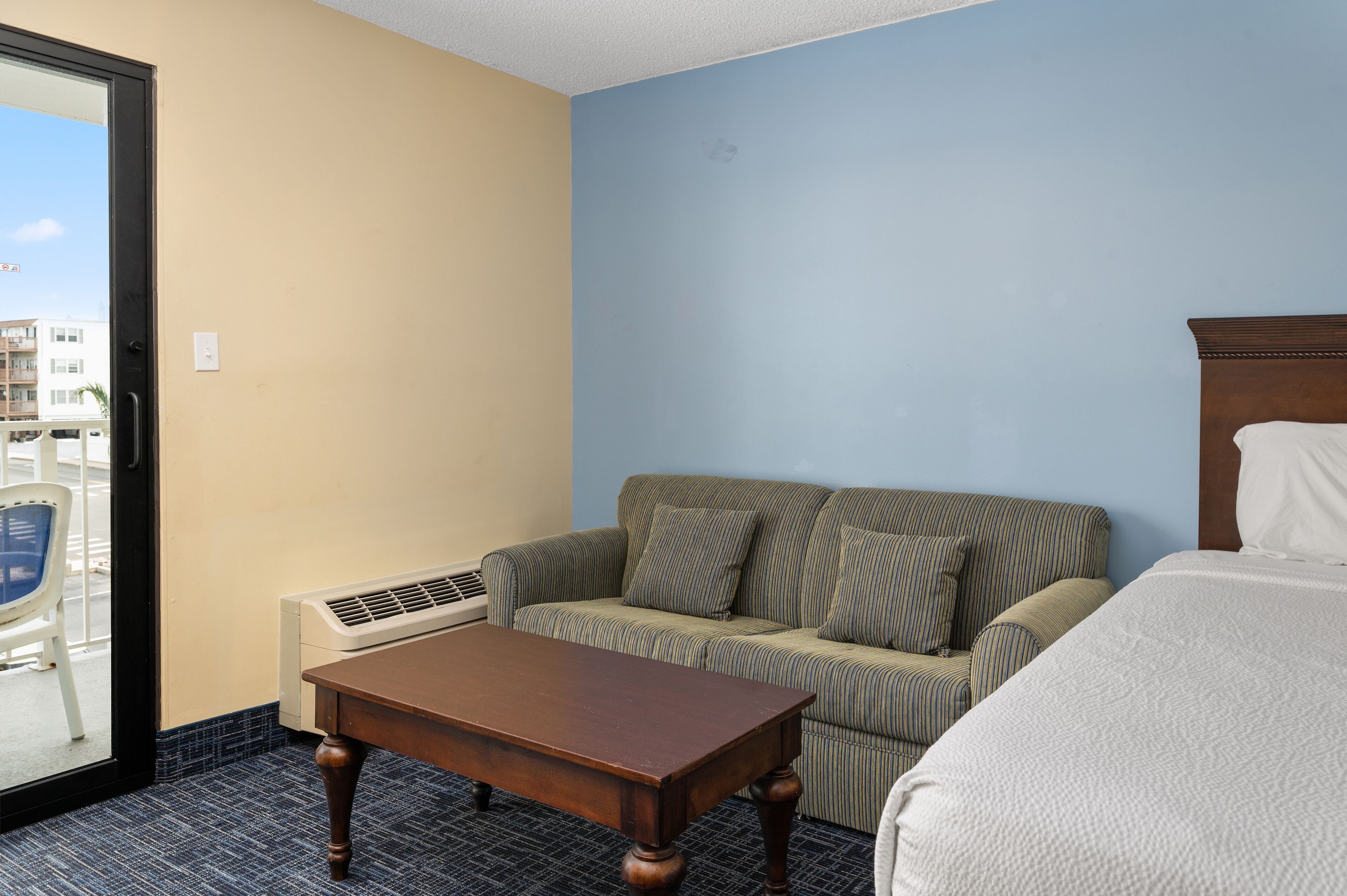 A hotel room with a sofa, a wooden table, and a bed.