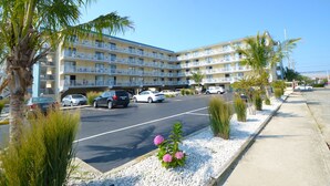 Ein mehrstöckiges Hotel mit Balkonen, einem Parkplatz und Palmen.