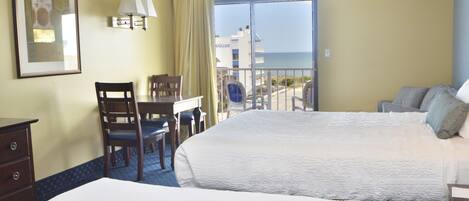 Une chambre d’hôtel avec un lit, un bureau et une chaise. Il y a une fenêtre donnant sur l’océan.