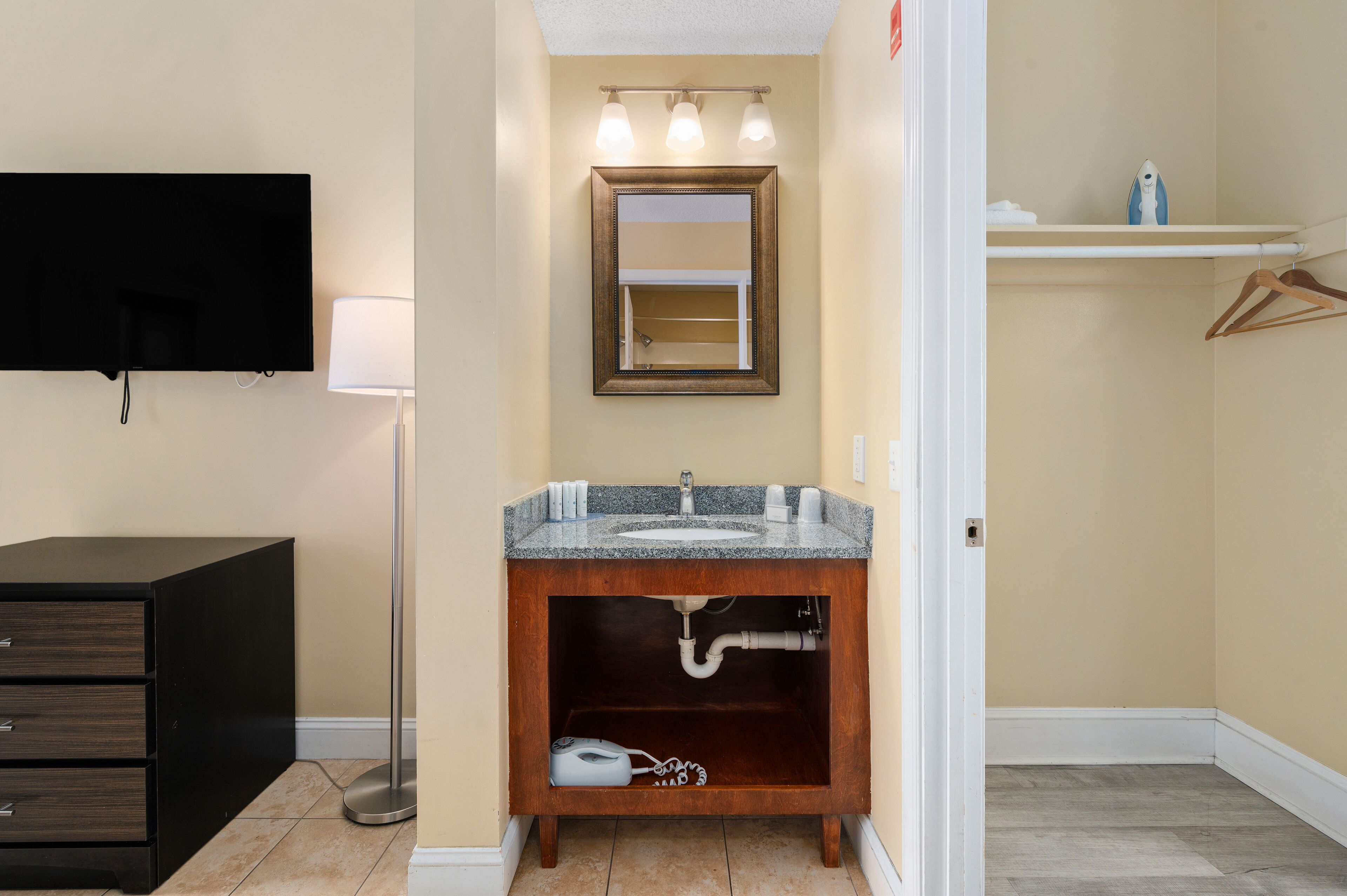 Une salle de bain avec un lavabo en granit, un miroir, un porte-serviettes, une lampe sur pied et un meuble noir.