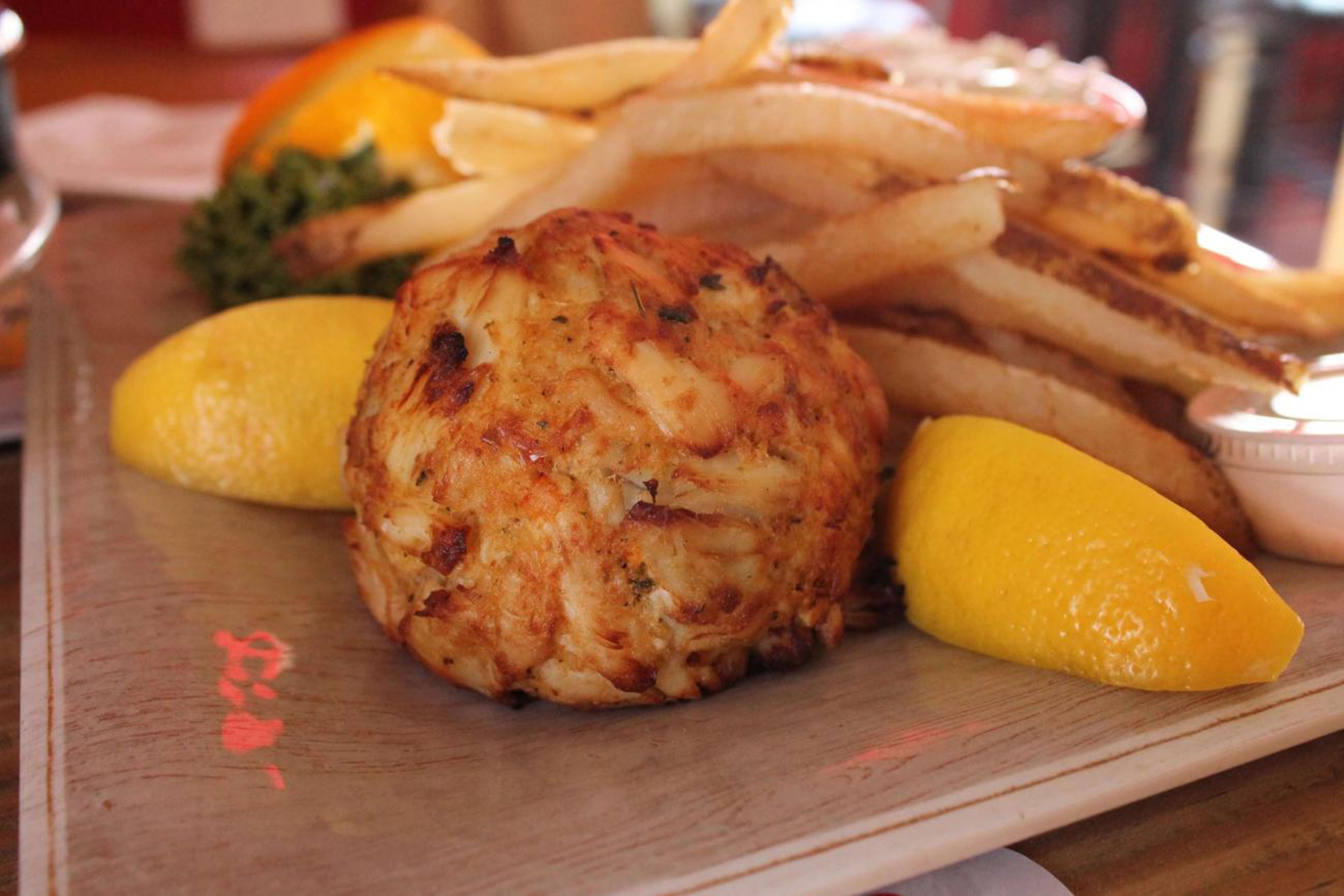 A plate with grilled chicken, lemon wedges, and French fries.