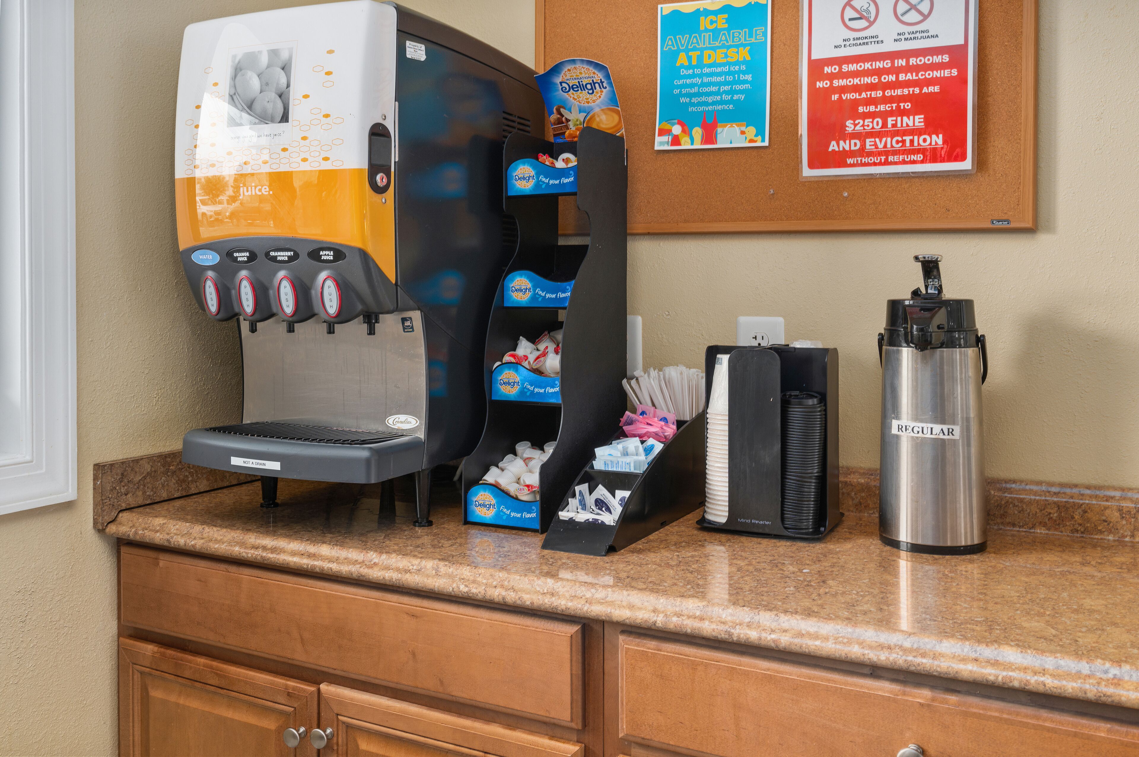 A self-service coffee machine with multiple drink options, a beverage dispenser, and a regular coffee pot on a counter.