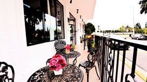 A balcony with outdoor seating, a railing, and a view of the street. - Notebook Miami Beach (Miami Beach)