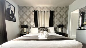A hotel room with a large bed, two bedside tables with lamps, a mirror, and a patterned wallpaper. - Notebook Miami Beach (Miami Beach)