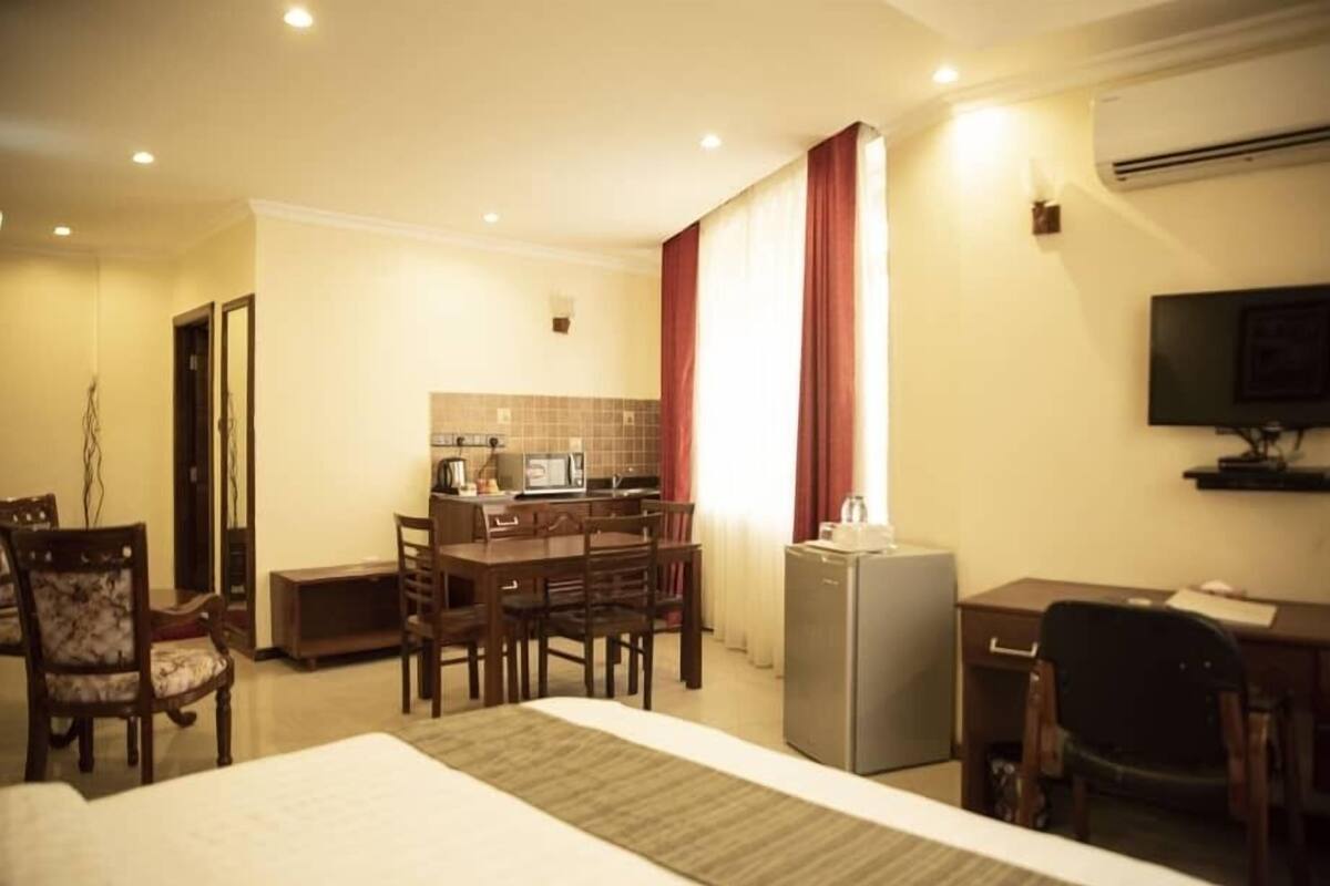 Une chambre d’hôtel équipée d’un lit, d’un bureau, d’une petite kitchenette et d’un téléviseur.
