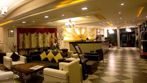 Un vestíbulo de hotel con suelo a cuadros, una recepción y zonas de estar.