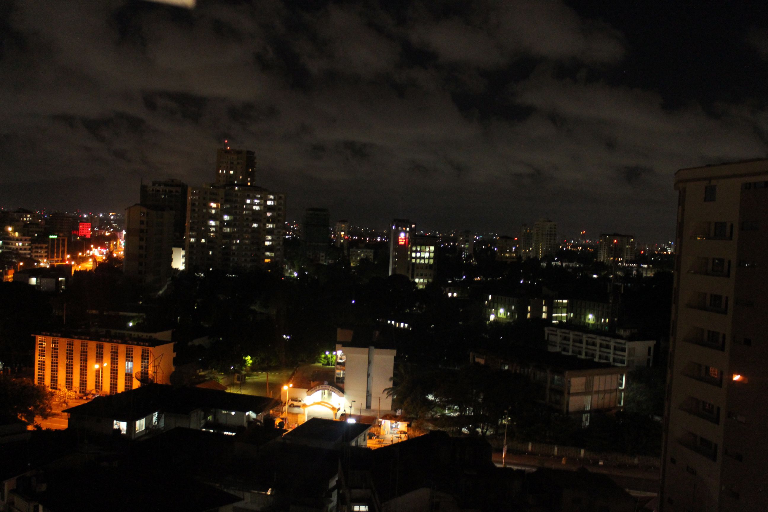 Eine beleuchtete Stadtlandschaft bei Nacht mit Wolkenbewölkung.