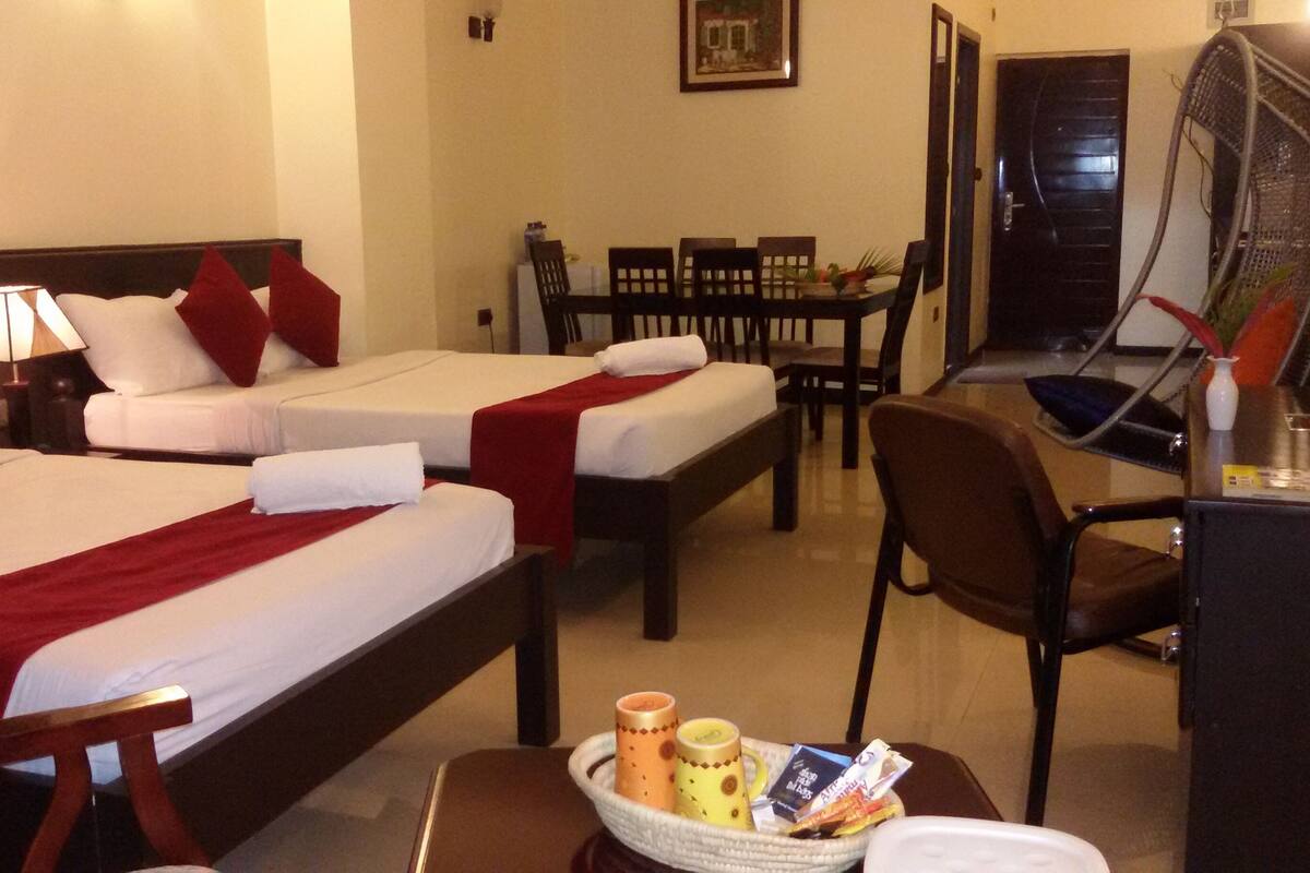 Une chambre d’hôtel avec deux lits, une table à manger et un bureau avec une chaise.