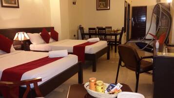 A hotel room with two beds, a dining table, and a desk with a chair.