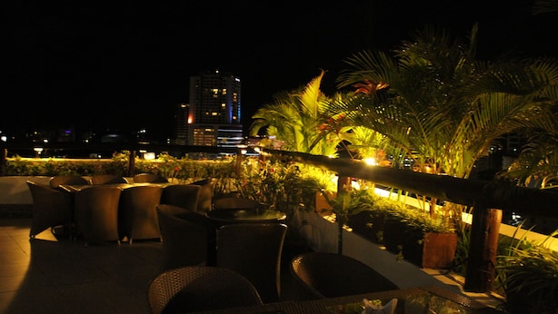 Terraza en la azotea con mobiliario exterior y vista al horizonte nocturno de la ciudad.