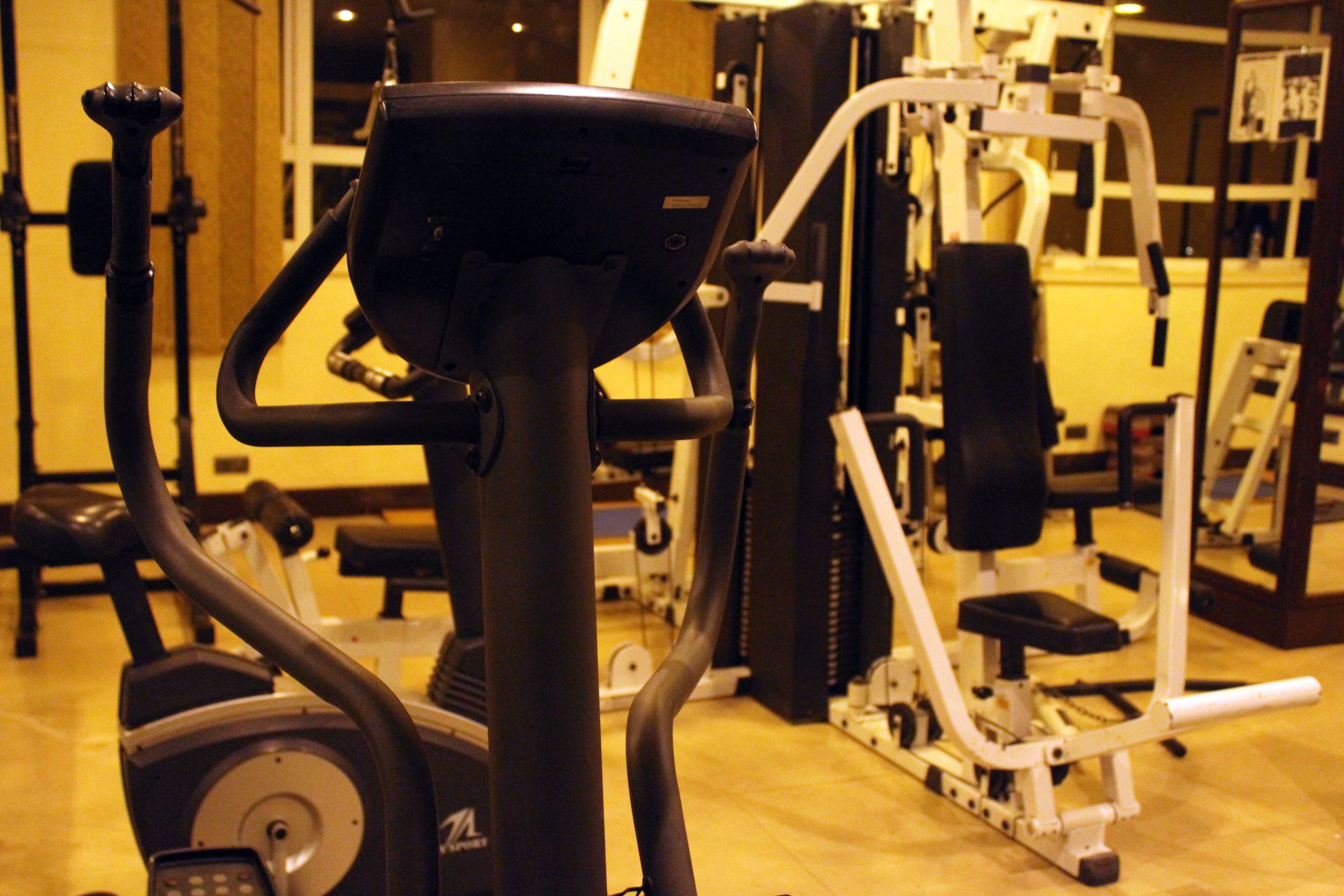 Un gimnasio con equipamiento de ejercicio que incluye una bicicleta estática, una cinta de correr y máquinas de pesas.