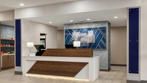 A reception desk with a modern design, a digital screen, and a blue geometric wall behind it.