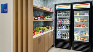 A hotel suite shop with snack shelves and two beverage refrigerators.