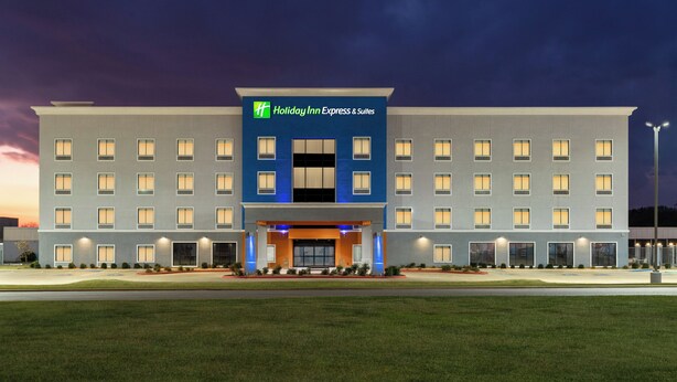 A Holiday Inn Express & Suites hotel with a modern facade, multiple windows, and a well-lit entrance.