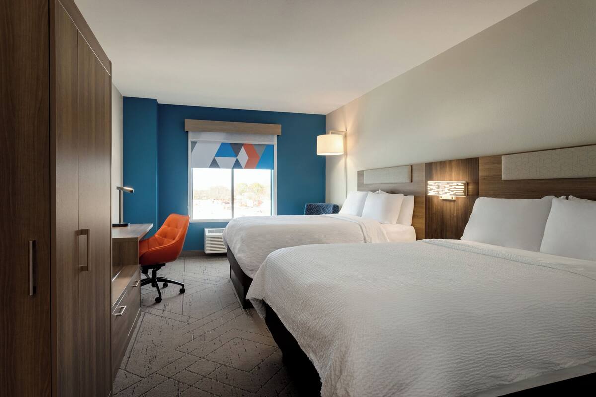 Ein Hotelzimmer mit zwei Betten, einem Schreibtisch und einem Stuhl.