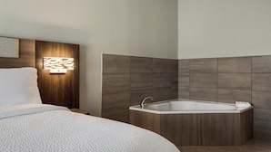 A modern bathroom with a freestanding bathtub, a wooden vanity, and a wall-mounted light fixture.