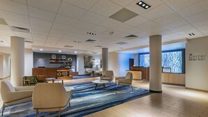 Un hall d’entrée moderne comprenant un comptoir d’accueil, un espace salon et une grande fenêtre donnant sur les arbres.