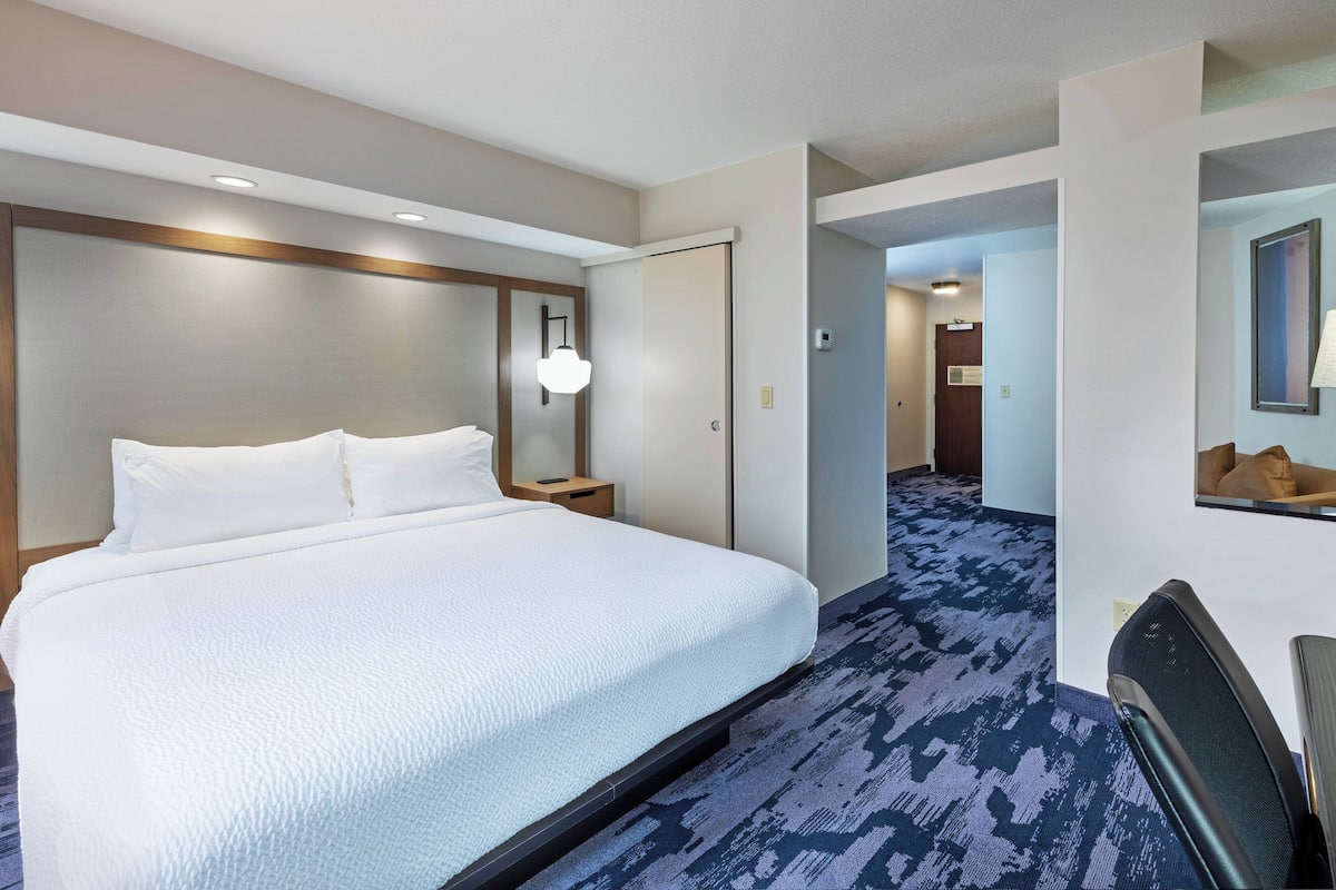 Een hotelkamer met een groot bed, nachtkastje, lamp en spiegel.
