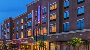 Un hôtel à plusieurs étages, doté d’une façade en briques, de nombreuses fenêtres et d’une grande enseigne lumineuse.