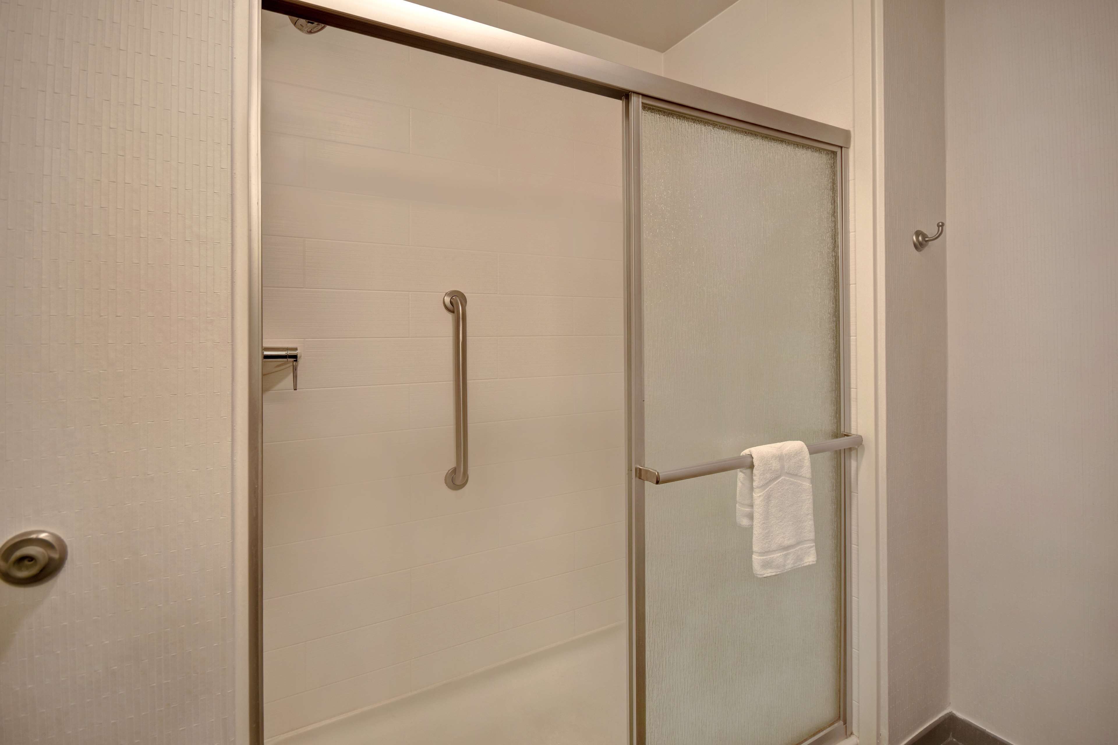 Ein Badezimmer mit Duschabtür, Handtuchhalter und Toilettenpapierhalter.