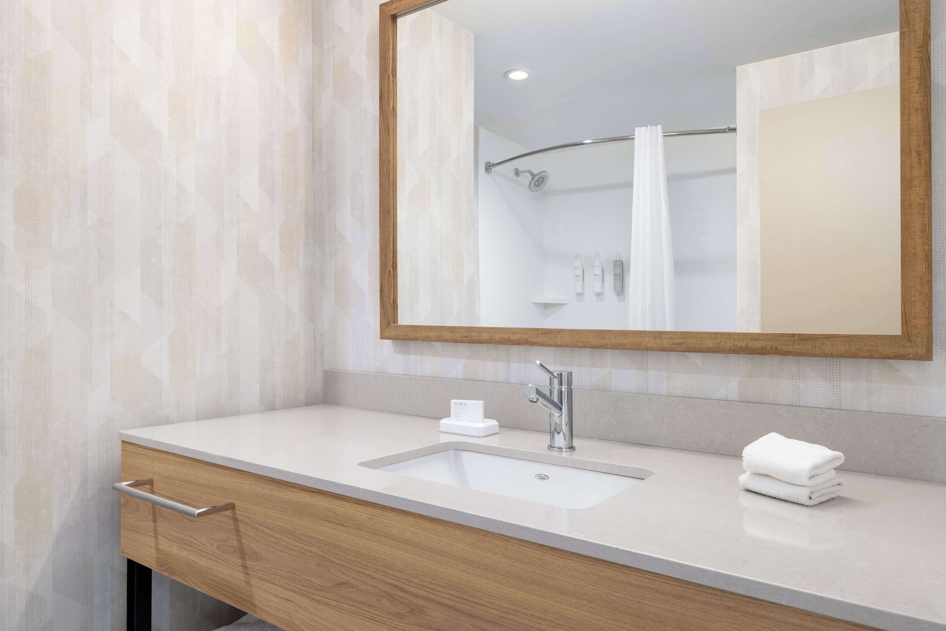Une salle de bain moderne avec un grand miroir, un lavabo et une douche.