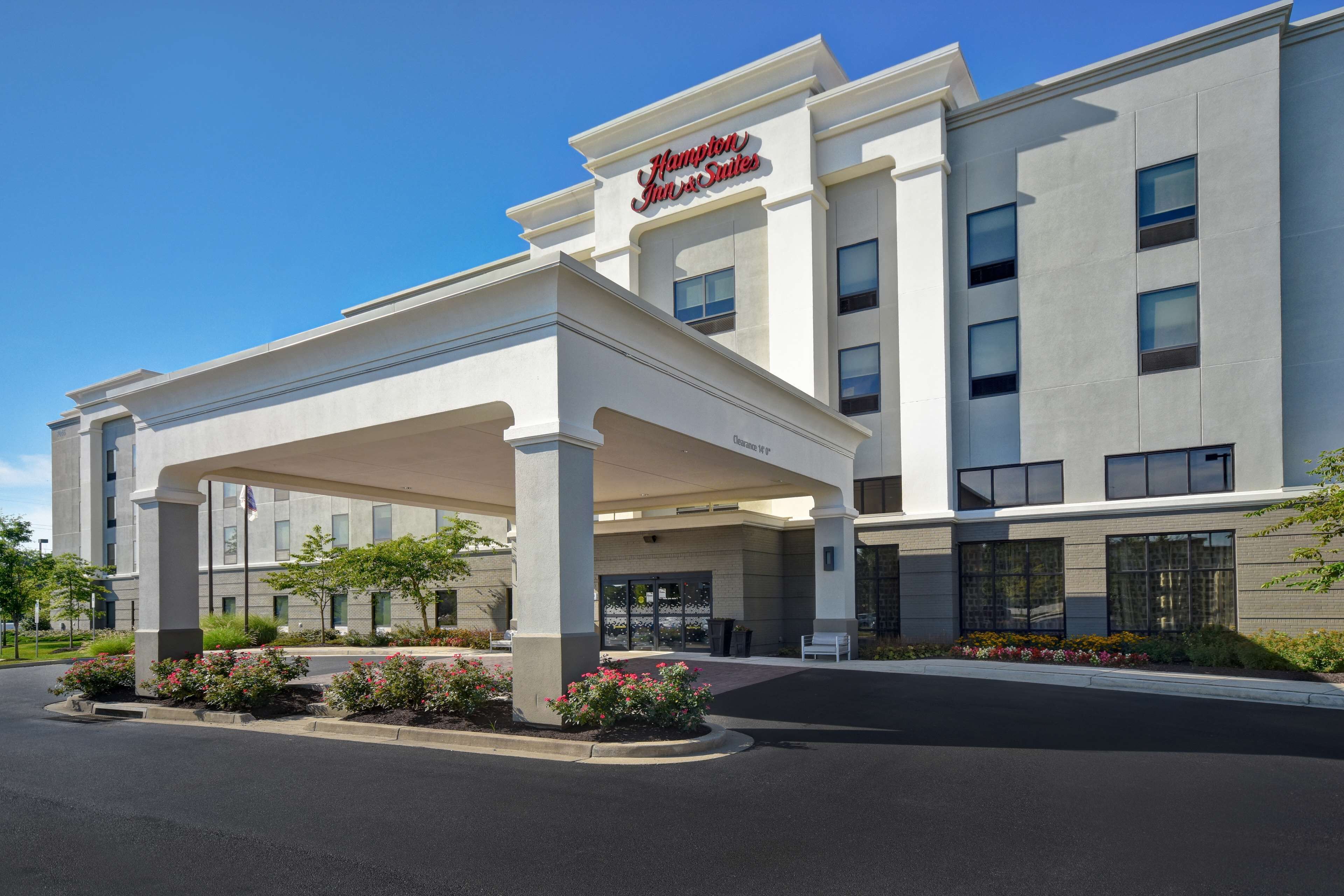 A modern hotel with a covered entrance, multiple floors, and a clear sky.