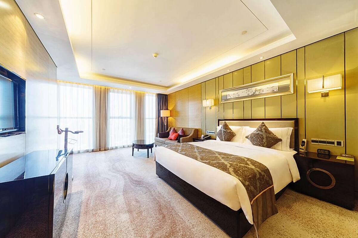 A hotel room with a large bed, a desk, and a TV.