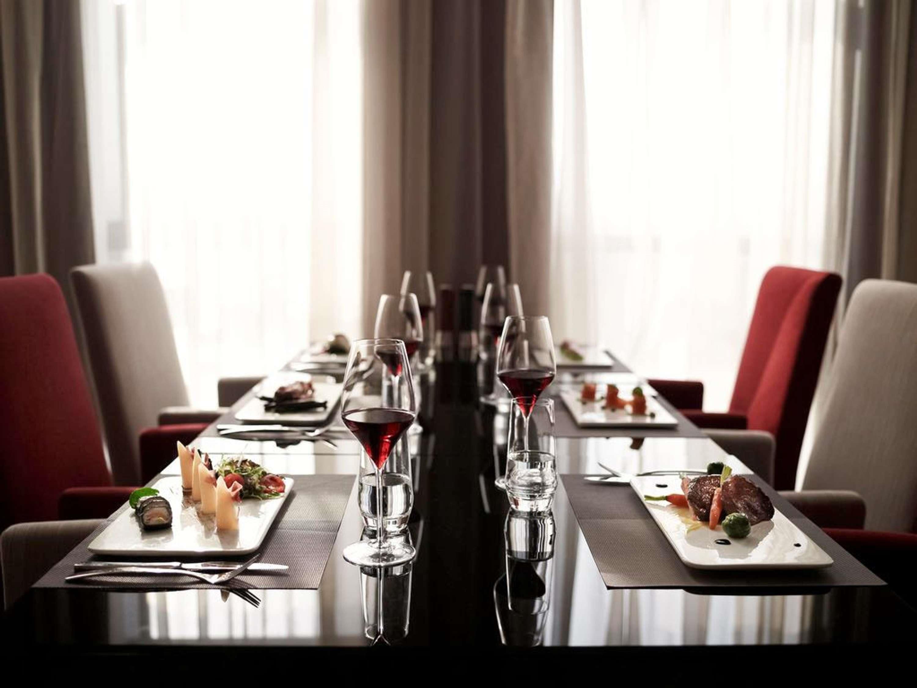 A long dining table with multiple plates of food, wine glasses, and cutlery.