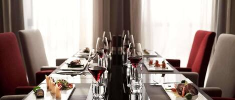 Una larga mesa de comedor con múltiples platos de comida, copas de vino y cubiertos.