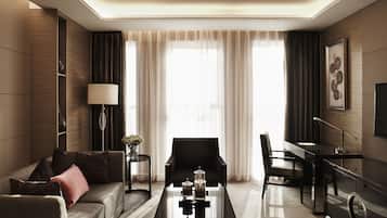 A modern hotel room with a sofa, a coffee table, a desk, and a TV.
