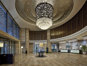 A spacious lobby with a large chandelier, high ceilings, and a central decorative table. - Pullman Wuxi New Lake (Wuxi)