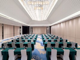 A conference room with a large oval table, rows of chairs, and a carpet with a floral pattern.