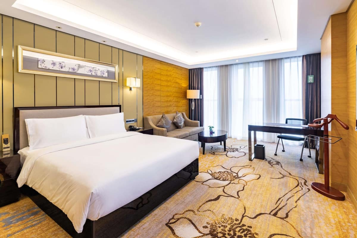 Une chambre d’hôtel avec un grand lit, un canapé, un bureau et une chaise.