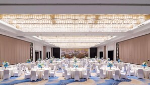 A large banquet hall with round tables, white chairs, and floral centerpieces. - Pullman Wuxi New Lake (Wuxi)